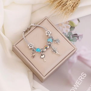 Detailed view of a silver snake chain bracelet with rainbow and fairy enamel charms