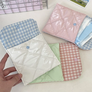 Close-up of portable quilted sanitary pad storage pouch with snap button and checked lining