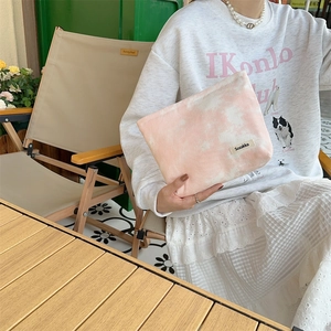 Close-up of pink tie-dye canvas toiletry bag with Sozakka label in a casual outdoor setting