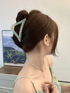 Detail of light green triangle claw clip with jade texture on model's hair