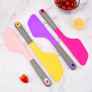 Set of four colorful silicone baking spatulas on a white marble background surface