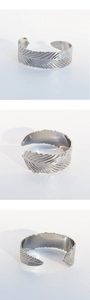 Dettagli del bracciale a piuma d'argento che mostrano la texture e il design aperto