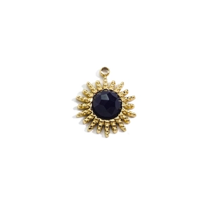 Detailed view of sun-shaped 14K gold pendant with black gemstone and radial rays