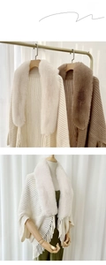 Close-up of knit shawl with faux fur collar, tassel edges, and vertical stripe texture