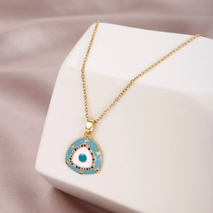 Golden evil eye necklace with colorful zircons on a white display stand and silk backdrop