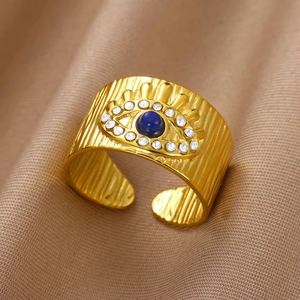 Detail of 18K gold evil eye ring with blue stone and white crystals on fabric