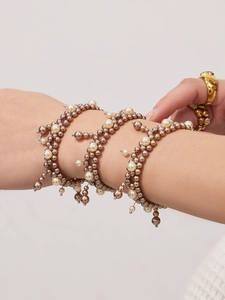 Detail shot of multi-layer bronze beaded bracelet with elegant white pearls and tassel design