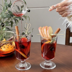 Long-handled glass stirring spoon for winter mulled wine cocktail with cinnamon and fruit