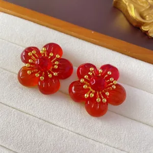 Vintage floral drop earrings with red petals and golden center on white velvet display