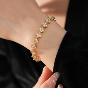 Gros plan d'un bracelet trèfle doré avec des pierres en zircone sur le poignet