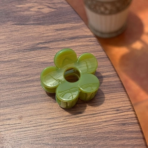 Détail d'une pince à cheveux fleur vert herbe avec finition acétate sur bois