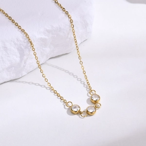 Golden stainless steel necklace featuring three round white zircons on a delicate chain