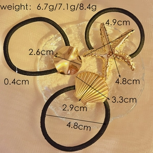 Starfish and shell gold metal hair ties set on a textured glass tray background