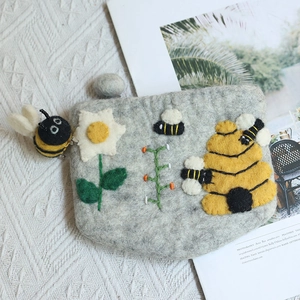 Handmade wool felt bee purse with floral embroidery on soft knit background