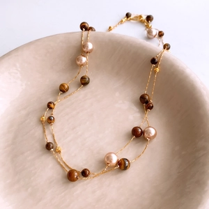 Close-up of vintage tiger eye beads and pearls on a double-layer gold chain necklace