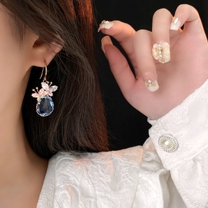 Gros plan sur une boucle d'oreille goutte bleue avec papillon en zircone au lobe