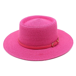 Dettaglio del cappello di paglia fucsia con cinturino in pelle e fibbia dorata