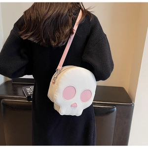 Macro view of white skull-shaped crossbody bag with pink leather accents and silver clasps