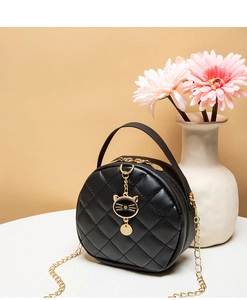 Close-up of black quilted mini bag featuring a gold cat charm and chain strap