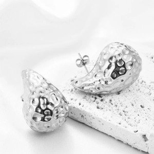 Détail des boucles d'oreilles goutte d'argent avec texture martelée sur pierre blanche