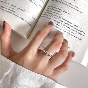 Detailed view of 925 silver heart ring with zircon on a model holding an open book