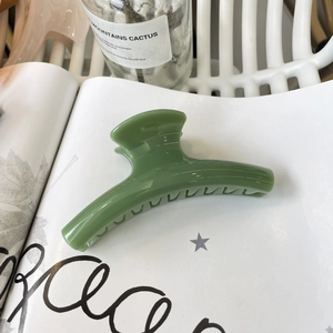 Detail of avocado green hair claw clip with ribbed texture on an open magazine