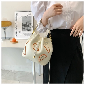 Detailed view of white drawstring bucket bag with orange fruit pattern on a shoulder strap