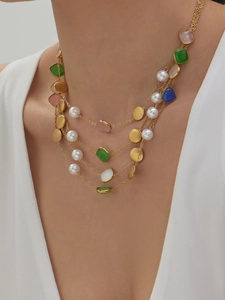 Detail einer mehrlagigen Kette mit bunten Katzenaugen-Steinen, Perlen und Goldplättchen