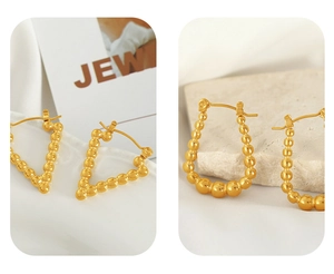 Macro view of gold beaded geometric V-shaped earrings with polished metallic spheres