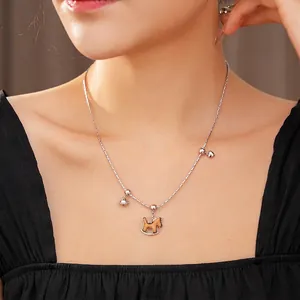 Collier argenté minimaliste avec cheval en bois, cœur et cloche porté par un modèle