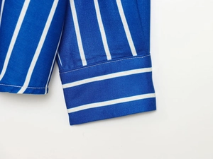 Gros plan du poignet d'une chemise à rayures bleues et blanches avec coutures soignées