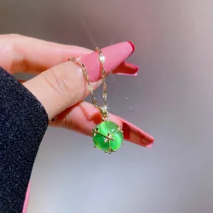 Nahaufnahme der grünen Katzenaugen-Kette mit goldener Sechs-Klauen-Fassung in der Hand