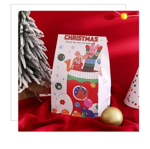 Vue détaillée de sacs-cadeaux de Noël en papier avec motifs festifs sur fond de satin rouge