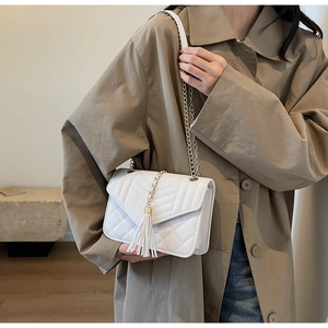 Close-up of white quilted crossbody bag with stylish long fringe and gold chain strap