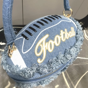 Detail of football-shaped handbag made of blue denim fabric with fringe and embroidery