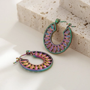 Macro shot of colorful iridescent hollow leaf earrings on a beige stone surface