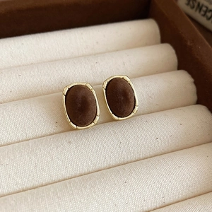 Close-up of gold-plated earrings with dark brown velvet texture in a jewelry box