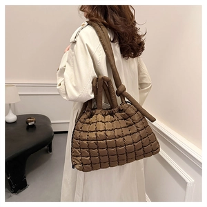 Detailed view of quilted puffer tote bag in brown featuring padded handles and shoulder strap