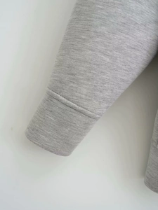 Detailed close-up of grey hoodie ribbed cuffs and high-quality knit fabric texture