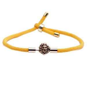 Adjustable yellow nylon cord bracelet with metallic lion head element on white background