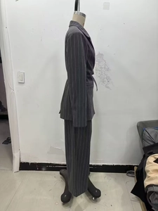 Détail d'un tailleur pantalon gris foncé à rayures avec veste ceinturée et pantalon large
