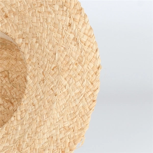Close-up of the natural raffia weave and wavy brim detail on a sun hat for women