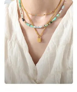 Detail of three-layer necklace with gold square locket and colorful stone beads