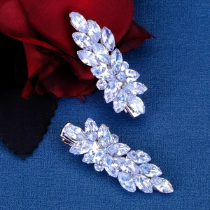 Elegant pair of silver bow hair clips with clear crystal zircon on dark blue fabric