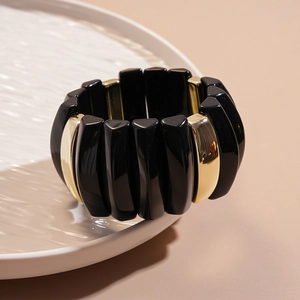 Close-up of flexible acrylic bracelet featuring glossy black and gold geometric segments