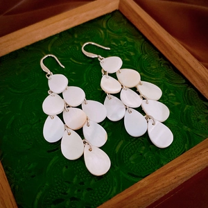 Detailed view of vintage water drop tassel earrings with white shell accents on wood tray