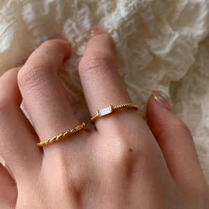 Close-up of gold s925 silver rings with twisted band and rectangular zircon on lace