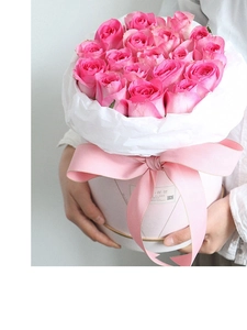 Close-up of pink rose flower box with pearlescent wrapping paper and ribbon bow decoration