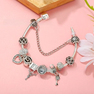 Macro detail of silver-plated heart charm bracelet with engraved lock and key pendants