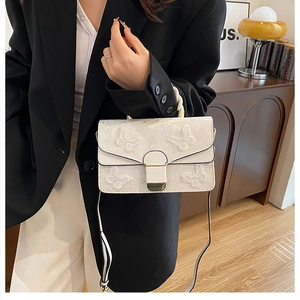 Détail du sac bandoulière blanc en similicuir avec motif papillon gaufré et boucle en métal